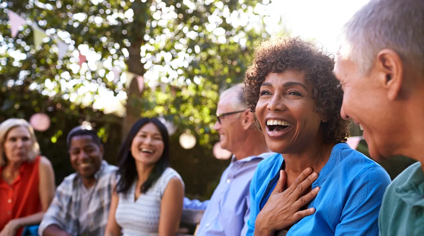 A group of older adults laughing together in warm sunlight — the kind of community feeling a study journey can include.